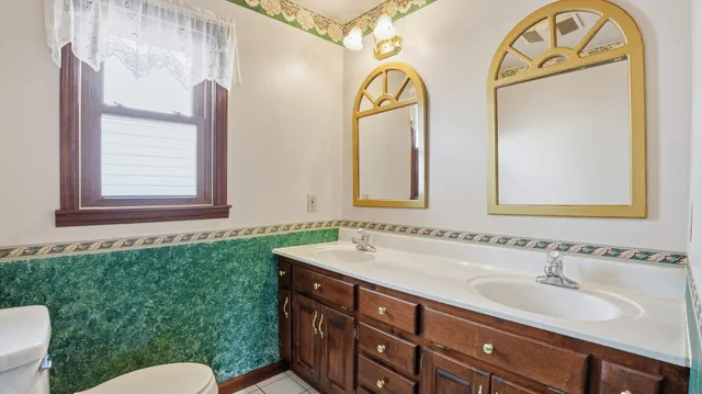 a bathroom with a granite countertop sink mirror vanity and toilet