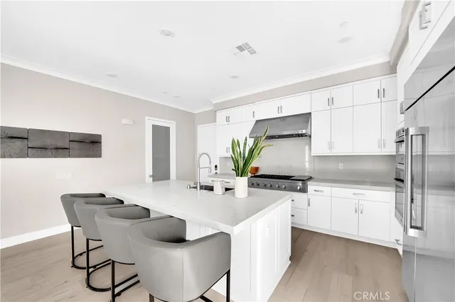 a kitchen with stainless steel appliances a sink a stove a table and chairs