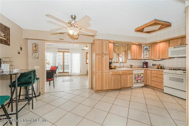 a large white kitchen with cabinets a stove a sink and a dining table view