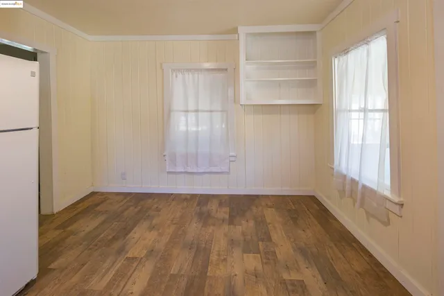 a view of an empty room with a window and wooden floor