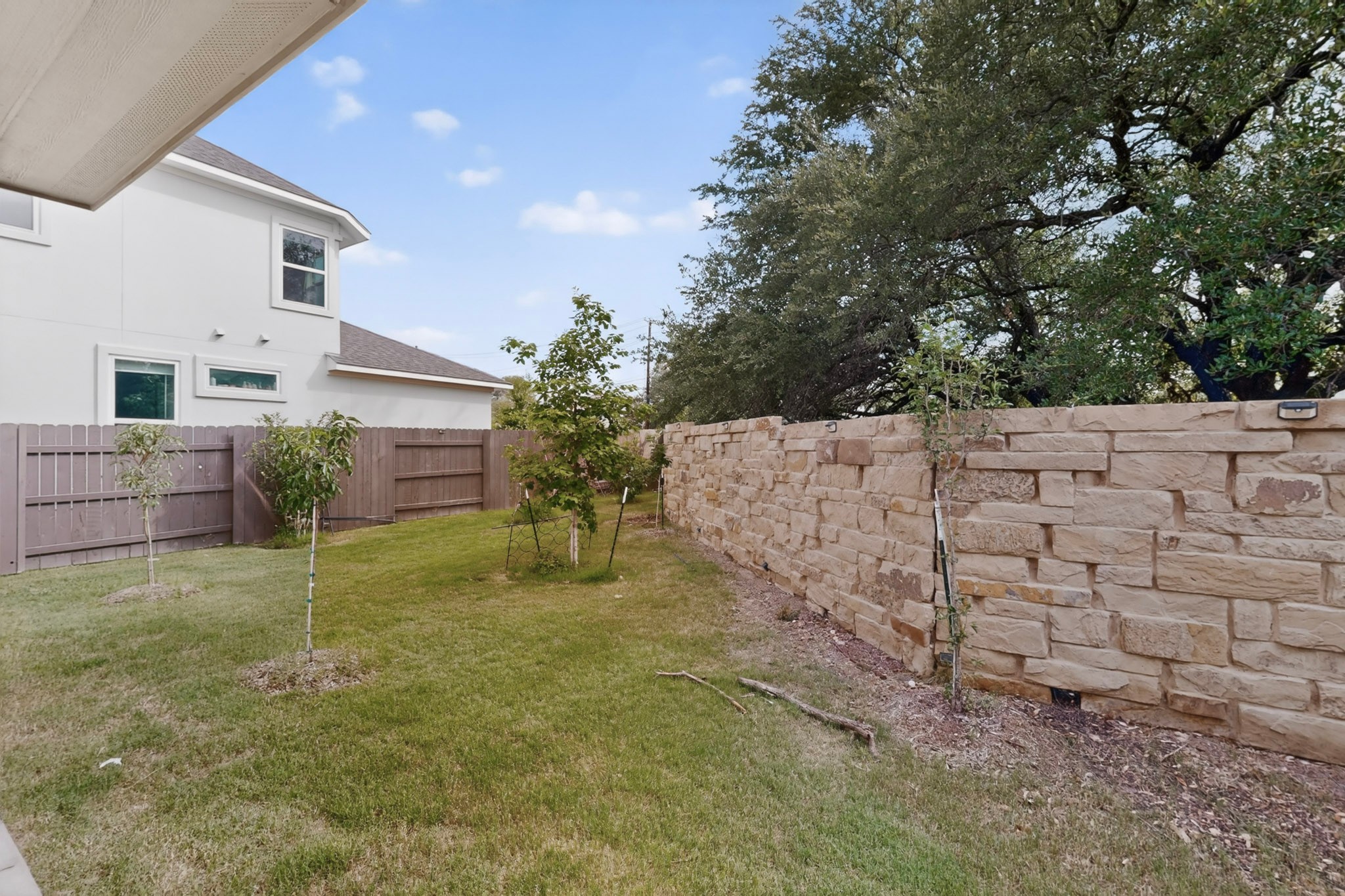 2605 Sam Bass Road, Unit 9 Round Rock, TX 78681 - Photo 38 of 38 A well-maintained lawn stretches towards a privacy fence and a robust stone retaining wall.