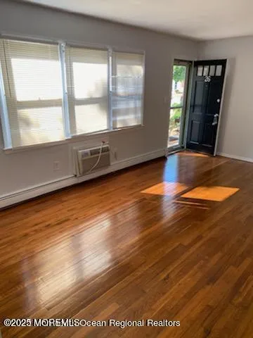 a view of an empty room with wooden floor and a window