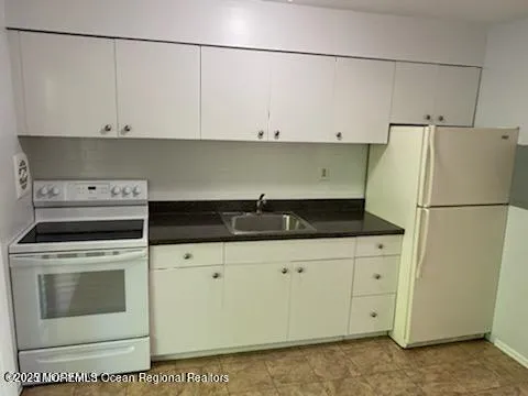 a kitchen with white cabinets and white appliances