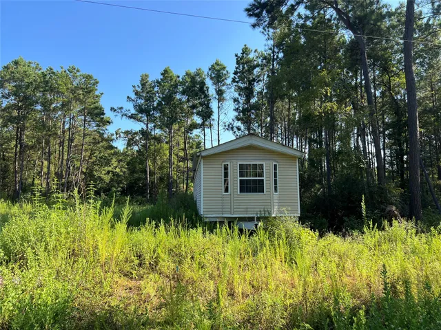 a front view of house with yard and trees in the background