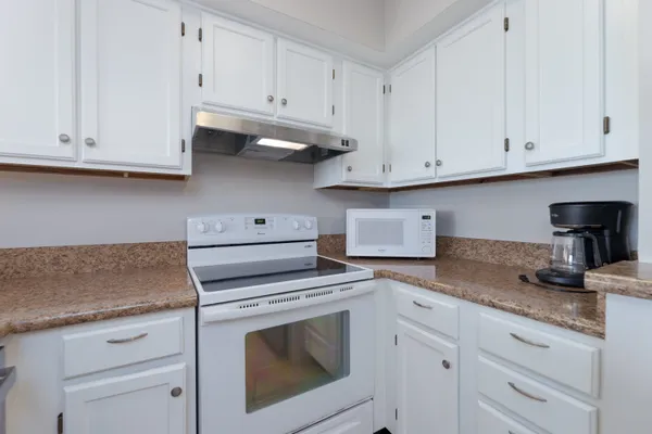 a kitchen with granite countertop white cabinets and a stove