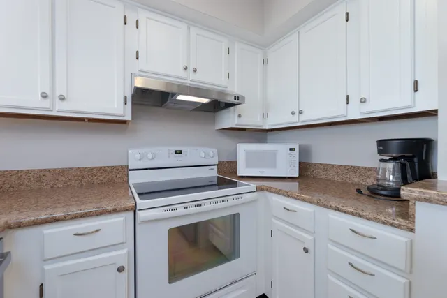 a kitchen with granite countertop white cabinets and a stove