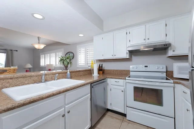 a kitchen with granite countertop white cabinets white appliances and a sink