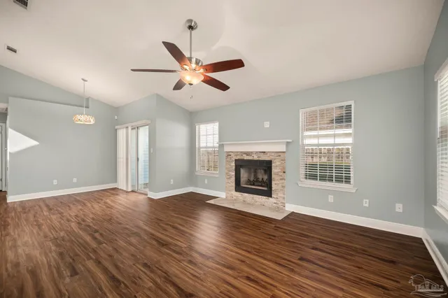 a view of an empty room with wooden floor and a fireplace