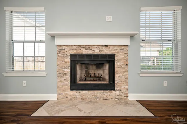 an empty room with wooden floor fireplace and windows