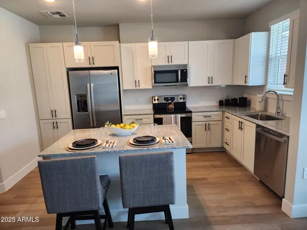 a kitchen with stainless steel appliances granite countertop a sink a stove a refrigerator and white cabinets