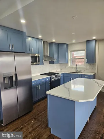 a kitchen with stainless steel appliances granite countertop a sink a stove a refrigerator and island with wooden floor