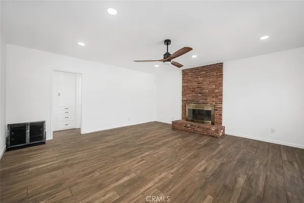 an empty room with wooden floor fireplace and windows