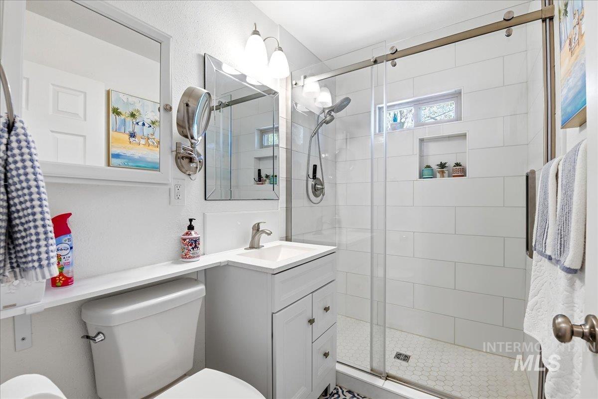 6710 West Ustick Road Boise, ID 83704 - Photo 16 of 42 Modern bathroom featuring a white vanity with integrated sink, brushed nickel faucet, and a large shower with subway tile surround