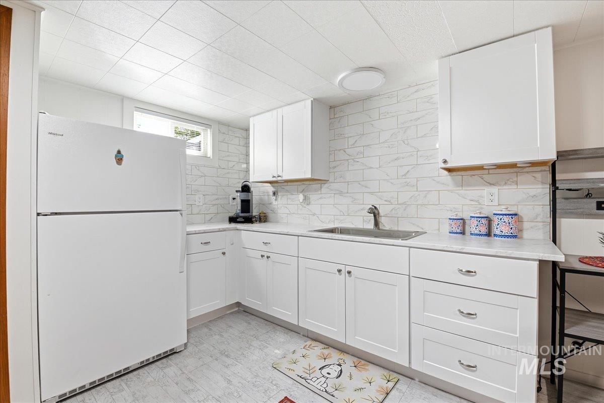 6710 West Ustick Road Boise, ID 83704 - Photo 22 of 42 Crisp white cabinetry with chrome hardware, complemented by a white subway tile backsplash and light-toned countertops