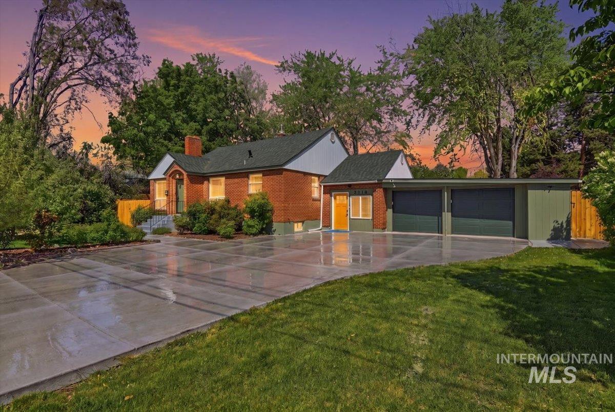 6710 West Ustick Road Boise, ID 83704 - Photo 3 of 42 Brick exterior with a dark green roof and chimney, featuring an expanded concrete driveway