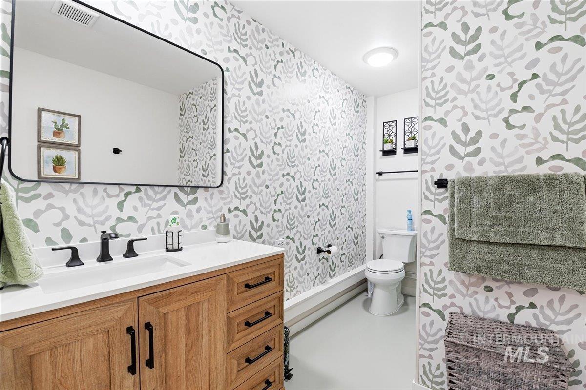 6710 West Ustick Road Boise, ID 83704 - Photo 35 of 42 Bathroom featuring a wood-finish vanity with a white countertop and black hardware