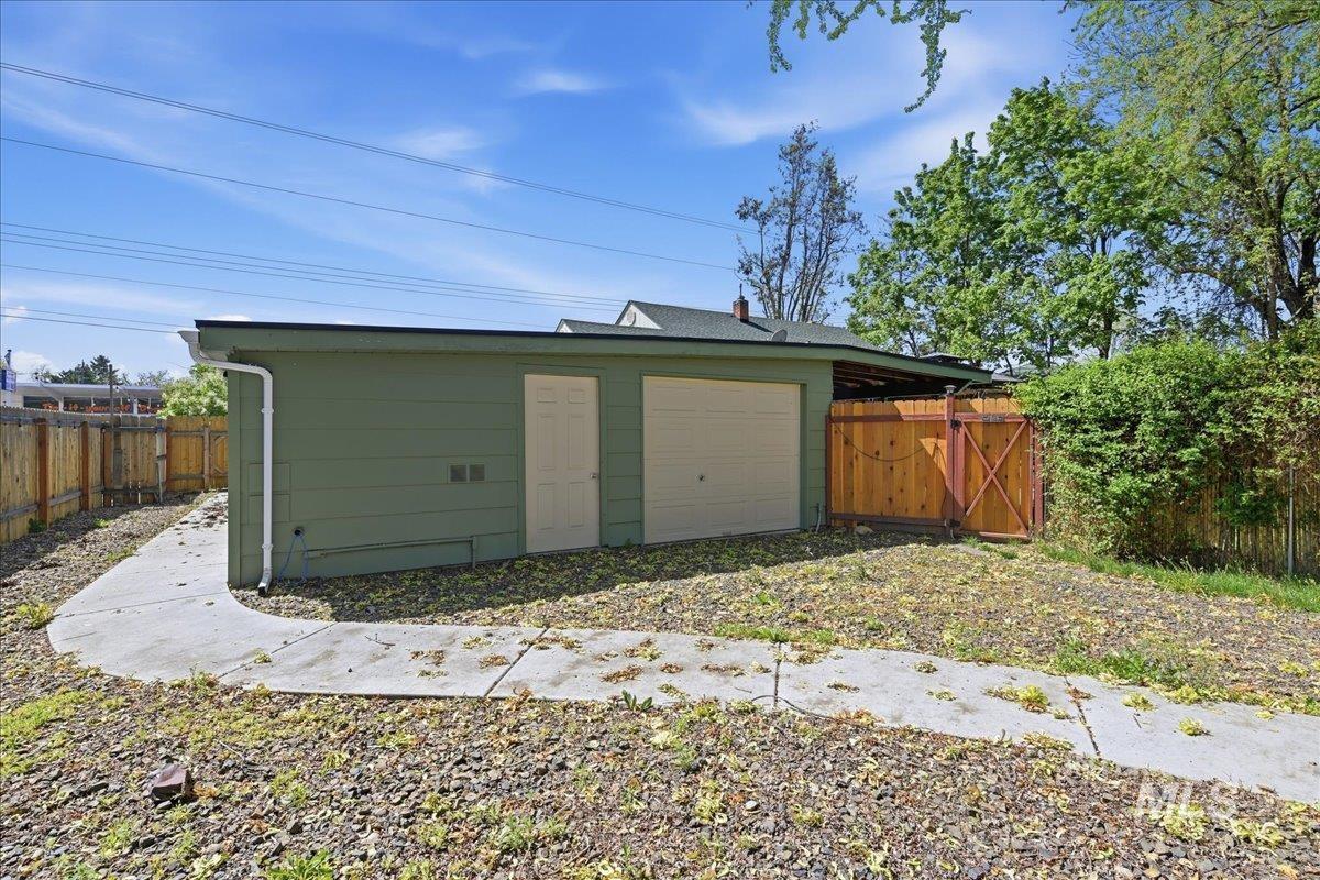 6710 West Ustick Road Boise, ID 83704 - Photo 37 of 42 Detached garage with two roll-up doors and a pedestrian entry door, featuring a light green exterior and a flat roof