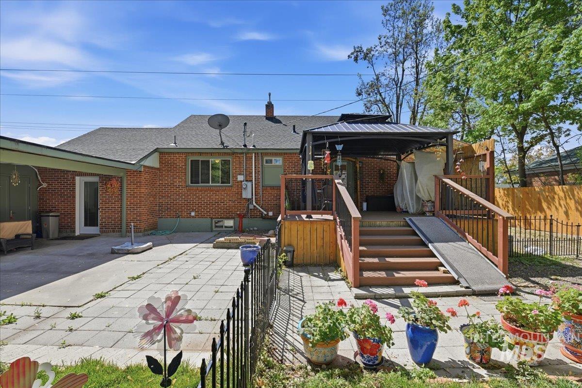 6710 West Ustick Road Boise, ID 83704 - Photo 39 of 42 Spacious backyard featuring a brick exterior, a covered deck with a ramp, and a large paved patio area