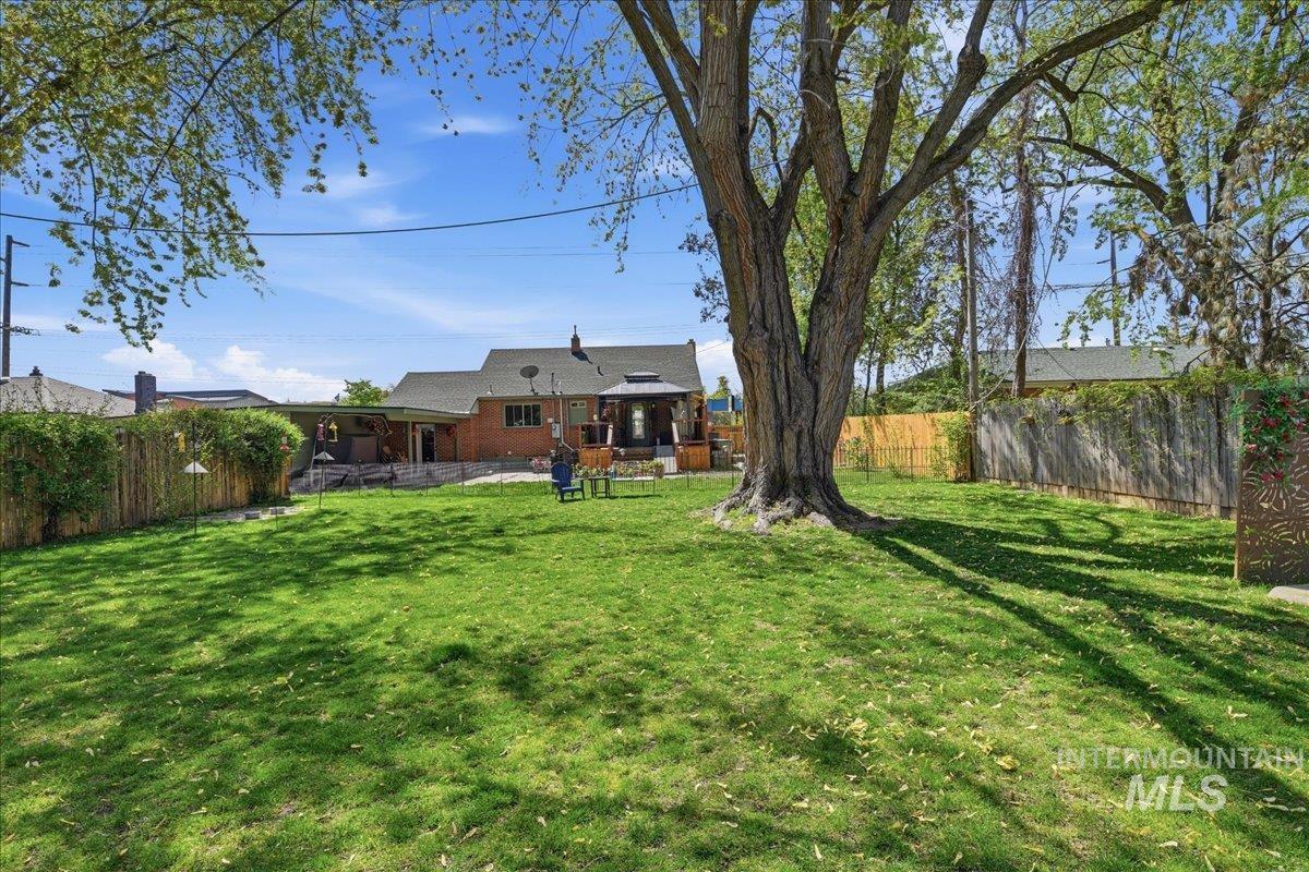 6710 West Ustick Road Boise, ID 83704 - Photo 42 of 42 Spacious backyard featuring a substantial mature tree providing natural shade, a manicured lawn, and a privacy fence