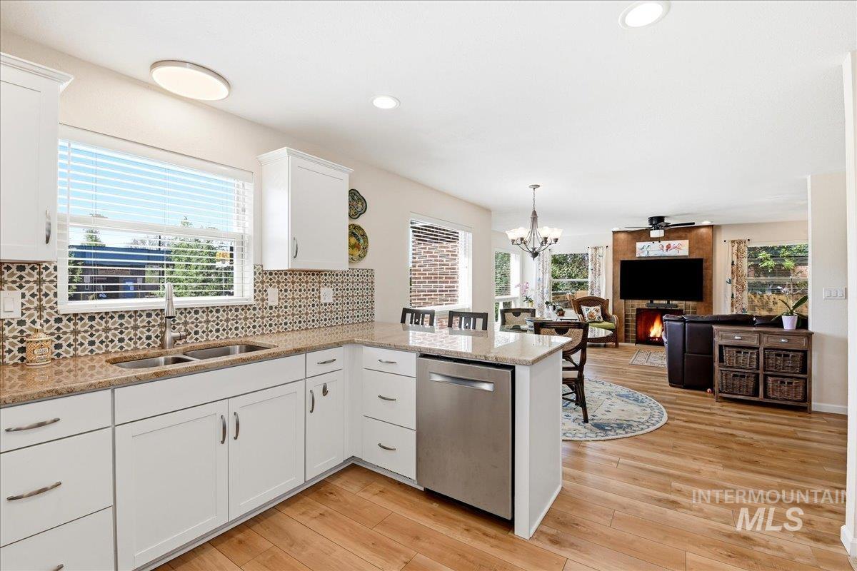 6710 West Ustick Road Boise, ID 83704 - Photo 10 of 42 Spacious kitchen featuring white cabinetry, a double basin stainless steel sink, patterned tile backsplash, and light-toned countertops