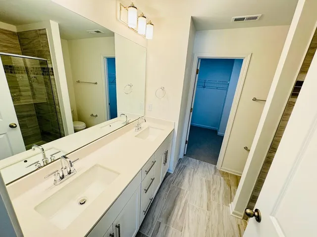 a bathroom with a double vanity sink and mirror with shower