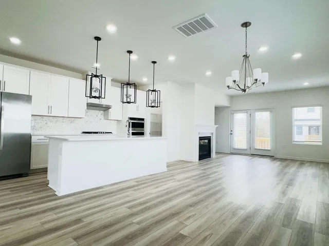 a view of a kitchen with granite countertop wooden floor stainless steel appliances and a window