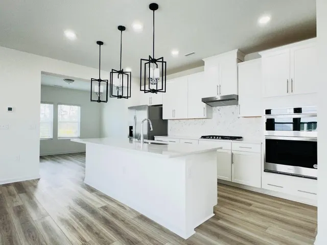 a kitchen with stainless steel appliances granite countertop a sink a stove and a wooden floors