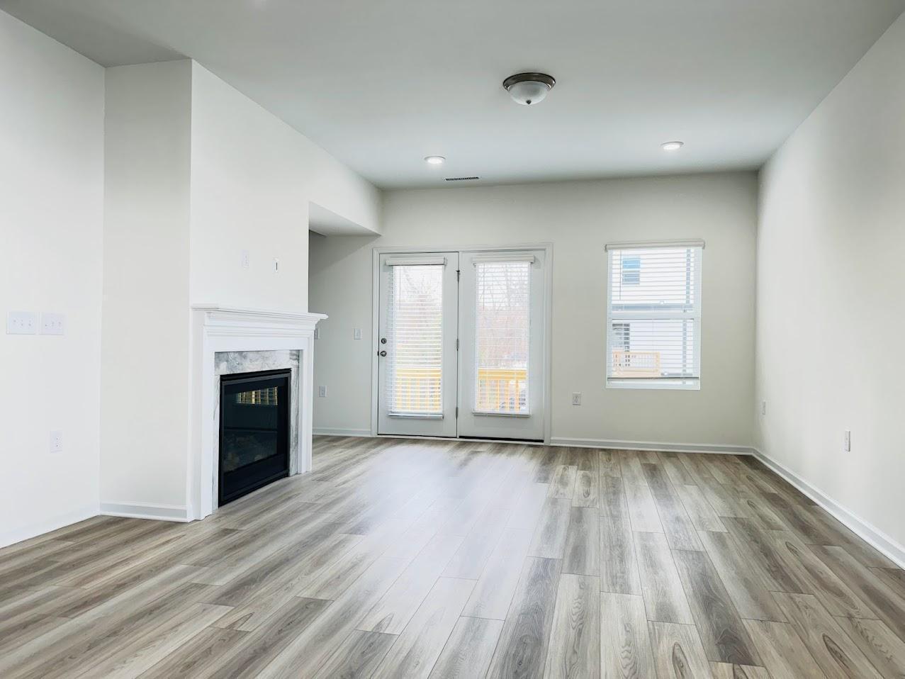 428 Sustainable Way Raleigh, NC 27610 - Photo 7 of 22 an empty room with wooden floor fireplace and windows