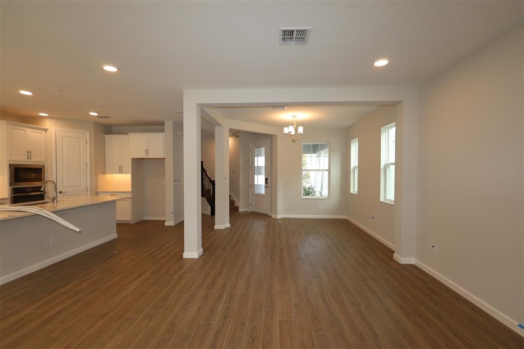 5184 Prairie Preserve Run St. Cloud, FL 34772 - Photo 28 of 36 a view of an empty room with wooden floor and a kitchen