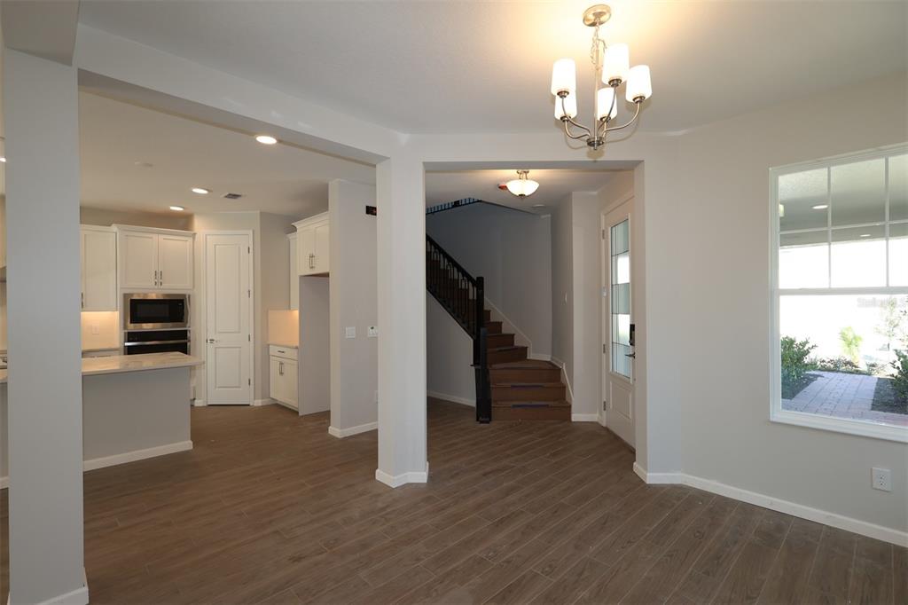 5184 Prairie Preserve Run St. Cloud, FL 34772 - Photo 3 of 36 a view of a hallway with wooden floor and a kitchen view