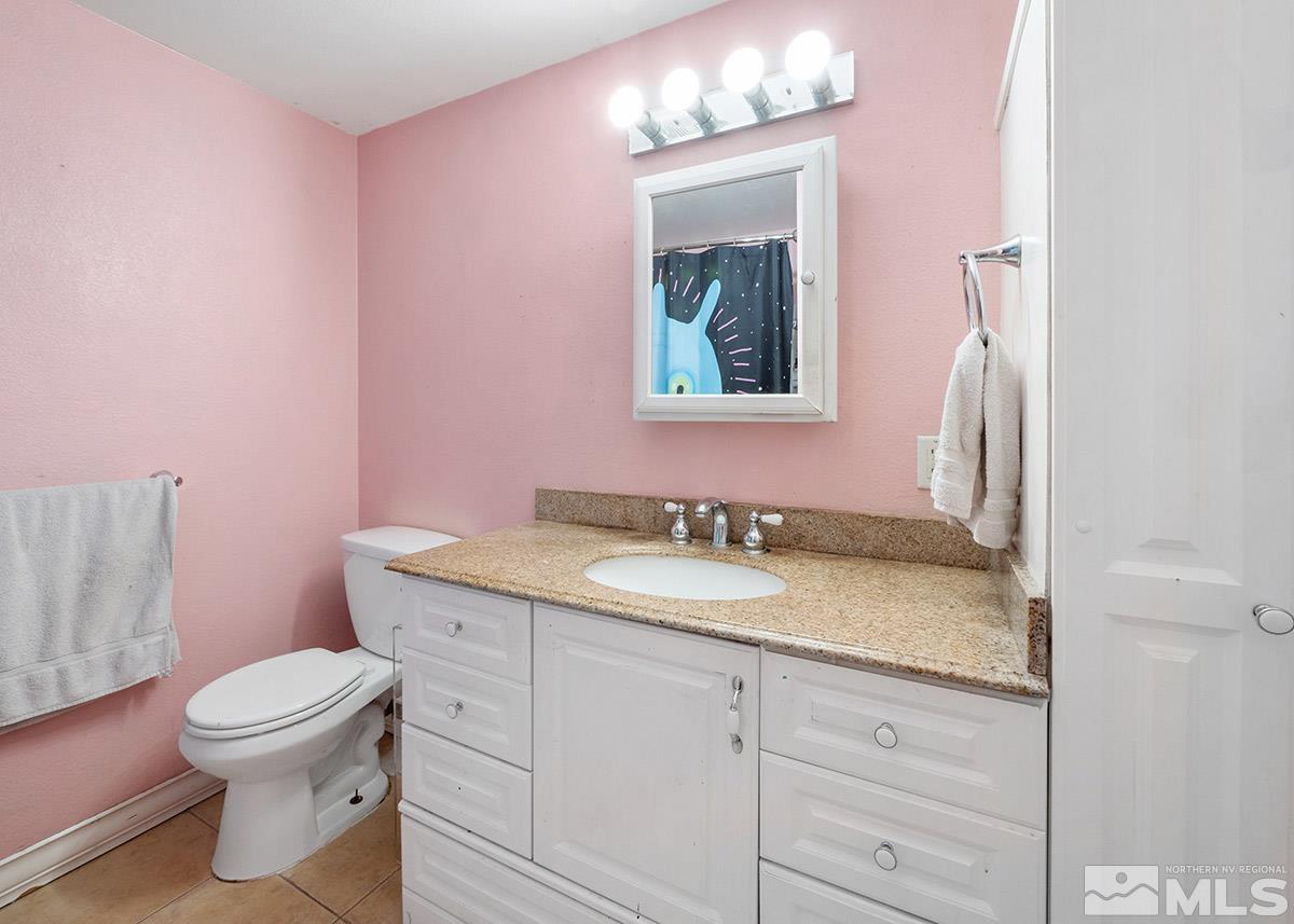 4155 Garlan Lane Reno, NV 89509 - Photo 17 of 24 a bathroom with a granite countertop sink a toilet and mirror