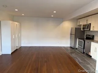 an empty room with wooden floor and electronic appliances