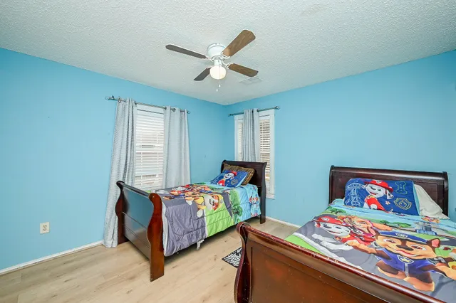 a bedroom with two beds and next to a window