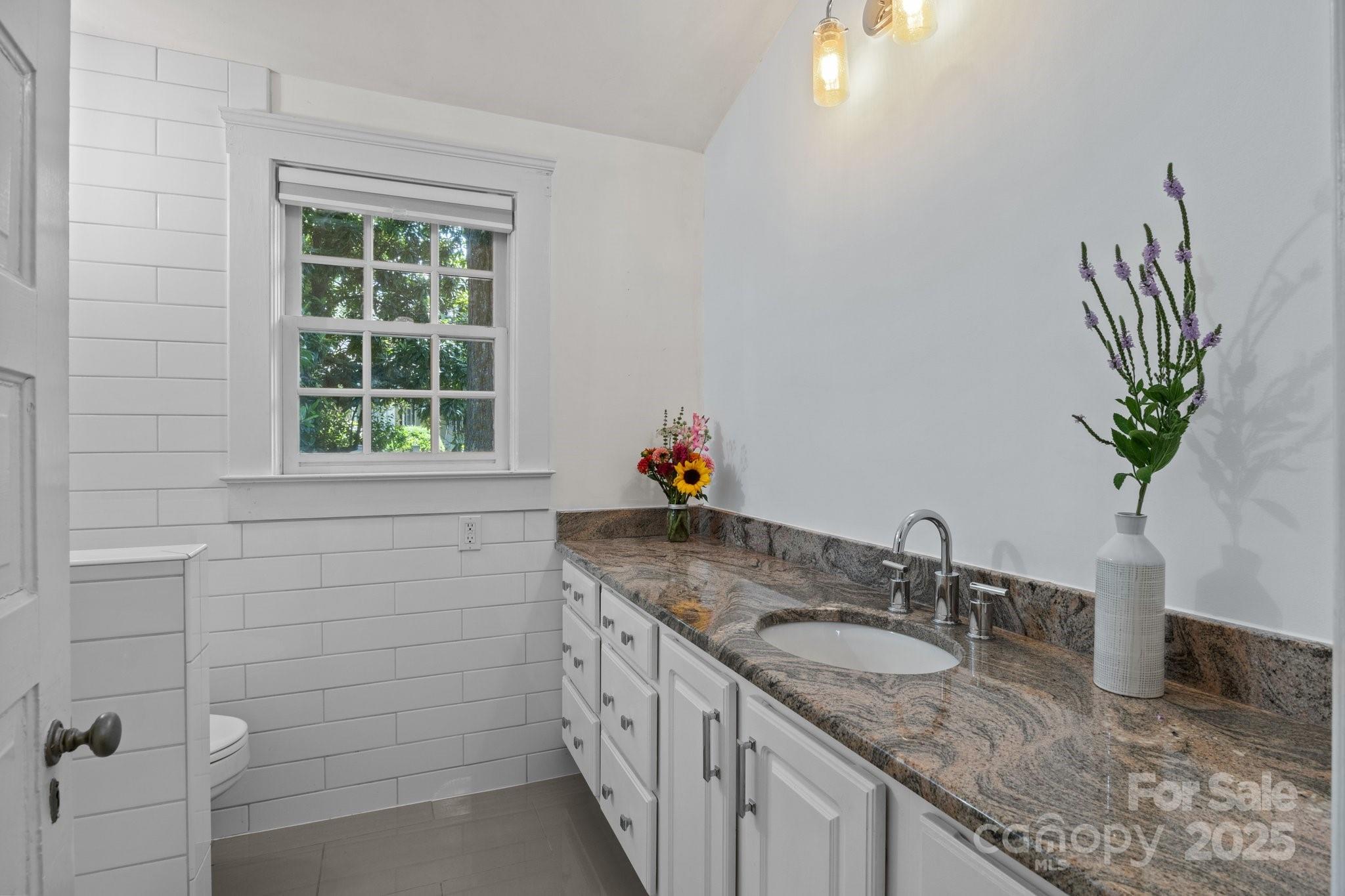 560 Concord Road Davidson, NC 28036 - Photo 25 of 34 a bathroom with a granite countertop sink a mirror and a window