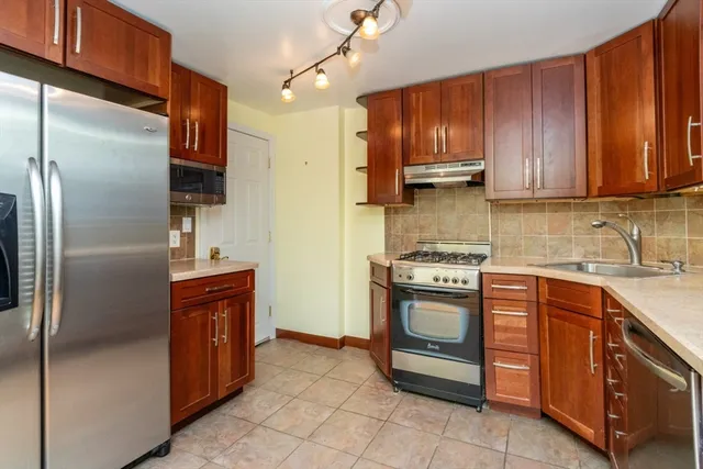 a kitchen with stainless steel appliances granite countertop a refrigerator a sink and wooden cabinets