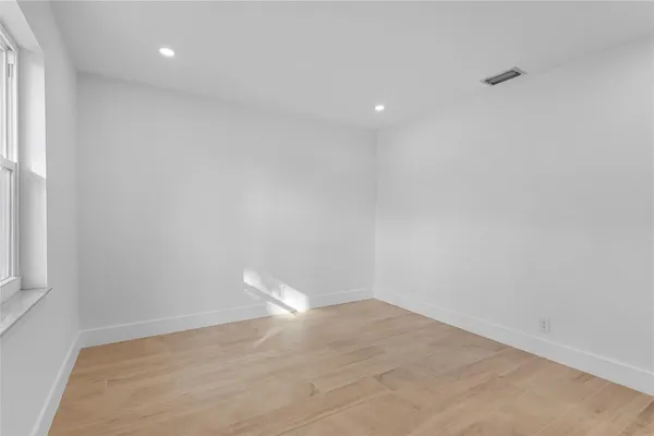 a view of an empty room with wooden floor and a ceiling fan