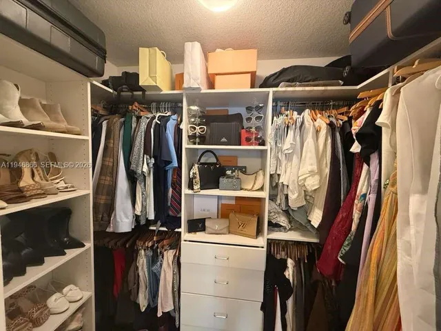 a view of walk in closet with clothes and shoes