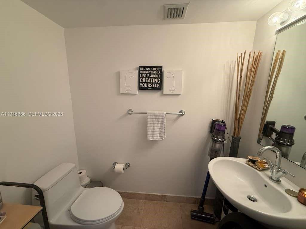 41 Southeast 5th Street, Unit 912 Miami, FL 33131 - Photo 8 of 23 a bathroom with a sink a toilet and a mirror