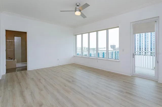 an empty room with wooden floor fan and windows