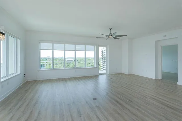 an empty room with wooden floor fan and windows