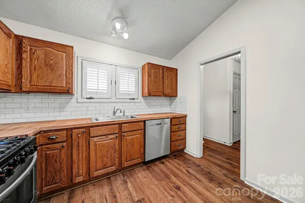 a kitchen with stainless steel appliances granite countertop a sink cabinets and wooden floor
