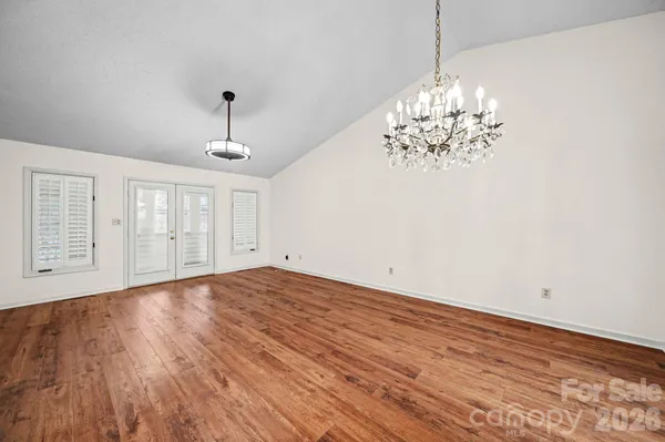 a view of empty room with wooden floor and chandelier