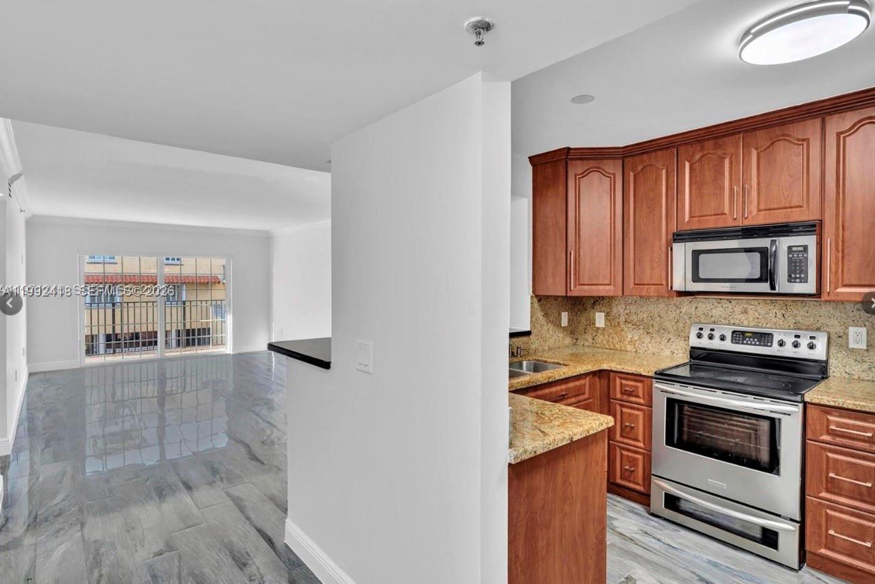 8900 Collins Avenue, Unit 304 Surfside, FL 33154 - Photo 12 of 18 a kitchen with granite countertop a stove top oven and cabinets