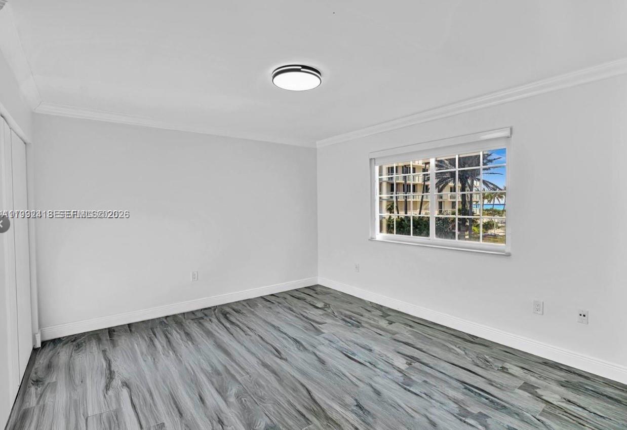 8900 Collins Avenue, Unit 304 Surfside, FL 33154 - Photo 3 of 18 an empty room with wooden floor and windows
