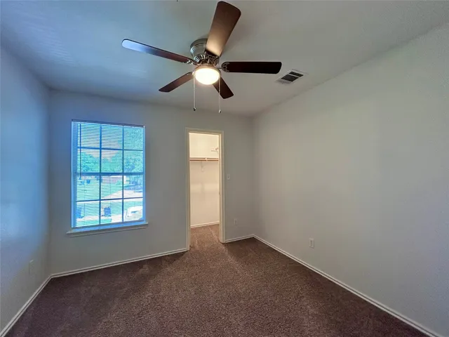 an empty room with windows and fan