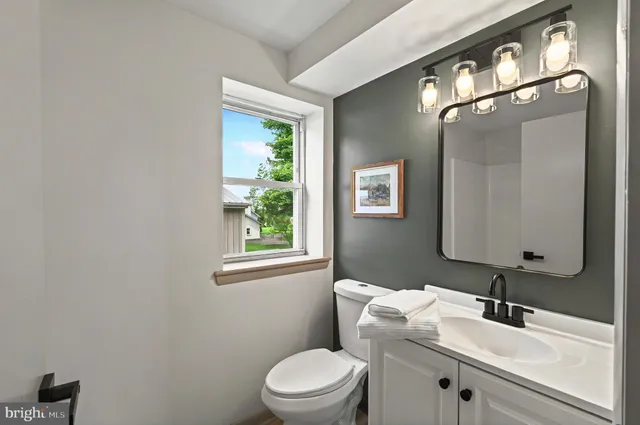 a bathroom with a toilet a sink a mirror and a window