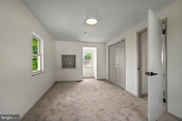 a view of an empty room with window and closet area