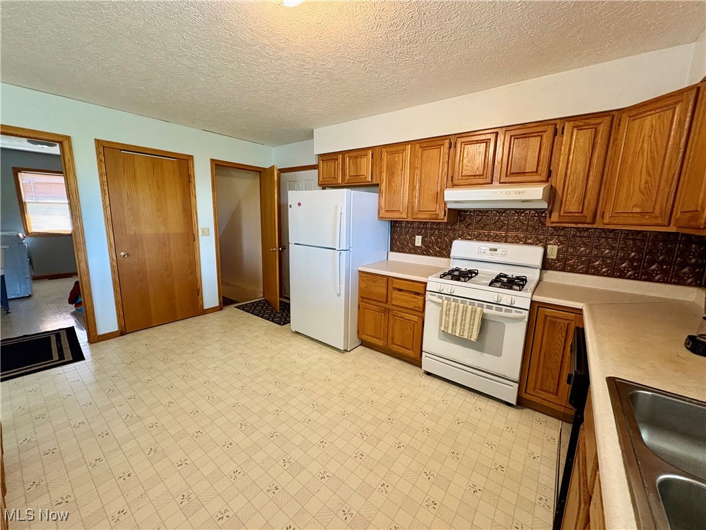 3333 Force Road Shreve, OH 44676 - Photo 10 of 26 Kitchen featuring white appliances, brown cabinets, light countertops, light floors, and a textured ceiling
