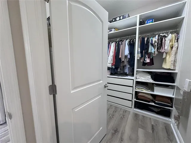a view of walk in closet with clothes and shoes