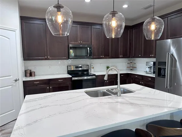 a kitchen with kitchen island granite countertop a sink cabinets and stainless steel appliances